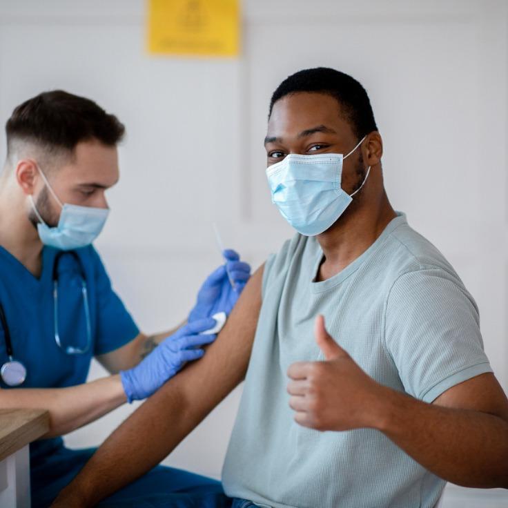 戴口罩的非裔美国人在冠状病毒疫苗接种期间竖起大拇指